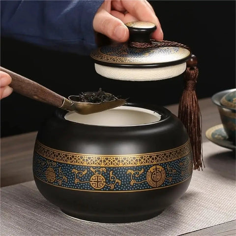 Airtight Ceramic Tea Canister With Silicone Seal Lid For Loose Leaf Coffee Beans Snacks And Nuts Keeps Kitchen Stash Crisp Locks In Flavor, black and gold ornate design, hand opening lid with tea scoop.
