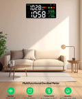Room with sofa and a multifunctional decibel meter displaying time, temperature, humidity, and other data on wall.