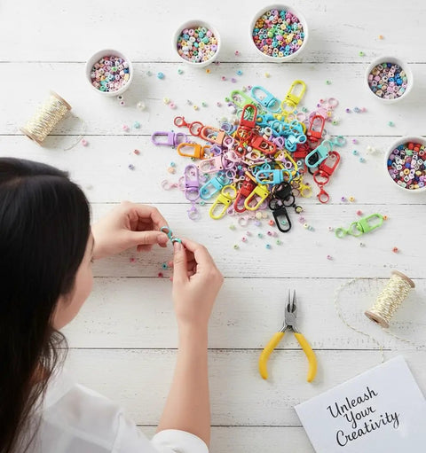 Person crafting with colorful 36 Pcs Colorful Swivel Snap Hooks Lobster Claw Clasps For Diy Crafts Jewelry Making on a workspace.