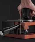 Top Shelf Solid Walnut Espresso Knockbox Station With Five Dedicated Slots For 51 54 And 58 Millimeter Portafilters, showing tamper usage.
