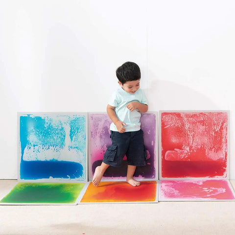 Child stepping on Six Assorted Color 12 by 12 Inch Liquid Floor Tiles Set for Kids, Kid Friendly Sensory Floor Tiles Where Color Flows With Every Step.