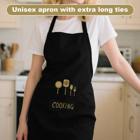 Person wearing black cooking apron with utensil design, unisex with extra long ties, in a kitchen setting.