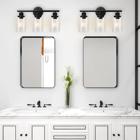 Modern 3 Light Vanity Light Fixture In Black With Clear Glass Shades seen above dual bathroom mirrors, sleek design, E26 base.