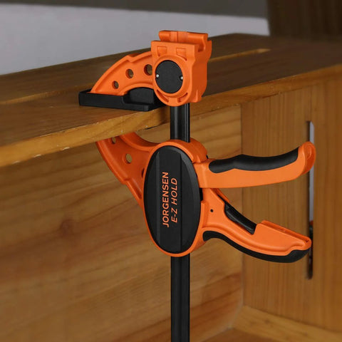 Jorgensen 12-inch ratchet bar clamp with E-Z Hold expandable spreader in orange and black.