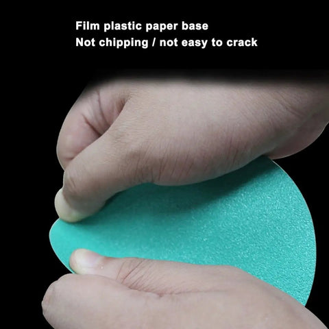 A close-up of hands holding a teal film plastic paper sanding disc showing its flexibility, part of Get The Ultimate 100pc Wet And Dry Sanding Discs Perfect For Random Orbital Sanders With Super Durable Hook And Loop Backing In Grits Ranging From 60 To 2000 For Total Makeover Jobs.