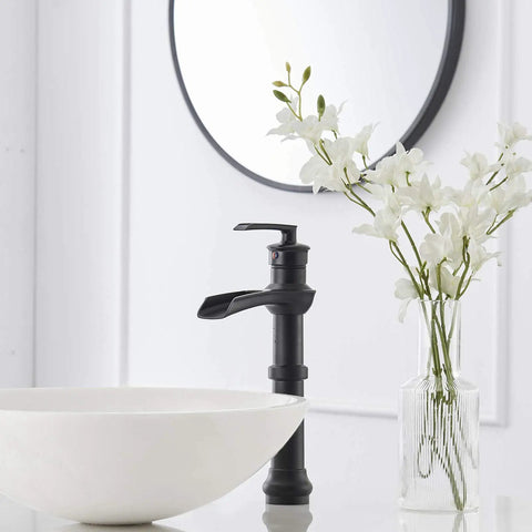 Dope Matte Black Vessel Sink Faucet With Waterfall Flow next to white ceramic bowl and flowers, sleek farmhouse style, no overflow.