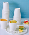 300 Pack Disposable Coffee Cups, 10 Oz White Hot Beverage Cups on table with drinks and desserts, sturdy leak proof rolled rim paper cups, thick walls and poly lining