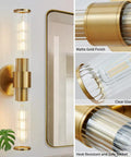 Vertical matte gold wall sconce with clear glass tube and safe socket features