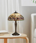 Tiffany-style stained glass table lamp on wooden side table next to a white sofa in a living room setting.
