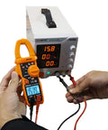 Person using Auto Ranging Clamp Meter For Electricians, Measures AC Current Up To 600A And AC And DC Voltage Up To 600V on power supply.