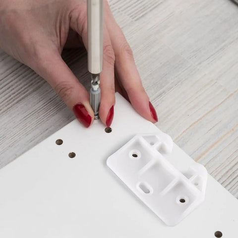 Person using a screwdriver to install a Slick White Plastic Drawer Track Guide Kit Packing 10 Pieces on a white board.