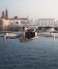 Mini 4 Pro Folding Drone With RC 2 Remote And Screen Fly More Combo 4K HDR Video Camera flying over a scenic water view