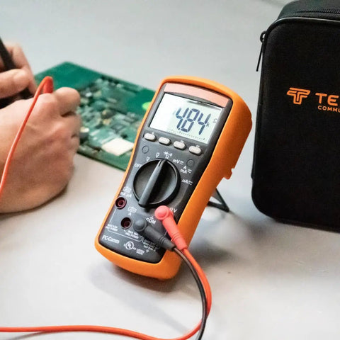 MM200 Digital Multimeter Auto Ranging 6000 Count Meter measuring voltage next to tech toolkit on workbench.