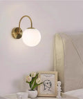 Gold Wall Sconce Mid Century Modern Wall Mount Light Hardwired Sconces Wall Light with Milky White Glass Shade Indoor Bedside Wall Lamps for Living Room Hallway above a bedside table.