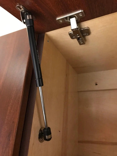 4 Pack 10 Inch Cabinet Gas Struts 100N Lift Supports for Cabinets Kit installed, showing soft close mechanism on a wooden cabinet door