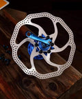 180mm 6 Bolt Stainless Steel Disc Brake Rotor for Road, Mountain, MTB and BMX Bikes on wooden table