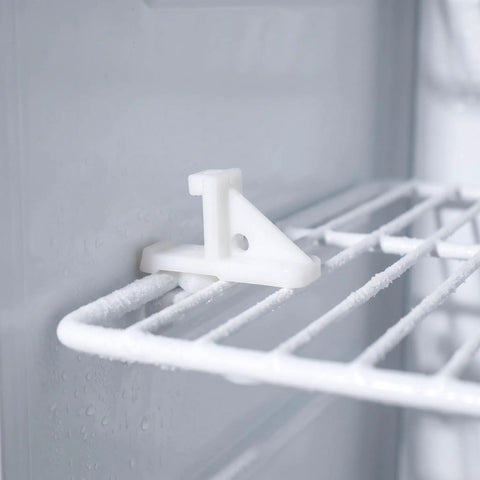 Close-up of a white locking retainer clip from the Ten Pack Refrigerator Shelf Support Clips And Freezer Bracket Set on a fridge shelf.