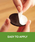 Hands peeling adhesive of Brown 32 Pack Felt Furniture Pads 1 Inch Round Self Stick Protect Hardwood Floors From Dings Dents And Scratches Easy To Apply Quick Install Chair Leg Caps For Tables Lamps And Decor