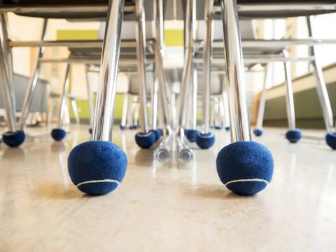 Blue 2.36 Inch Heavy Duty Precut Tennis Ball Floor Protectors on chair legs in classroom, fits furniture up to 1.5 inches.