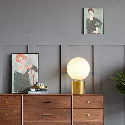 11 Inch Modern Gold Globe Table Lamp With Milk White Glass Shade And Sturdy Metal Base on a wooden dresser