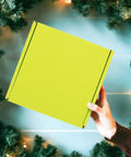 Person holding 10 Pack Green Corrugated Shipping Boxes For Mailing And Transport, Sturdy No Tape Or Glue Assembly against festive background.