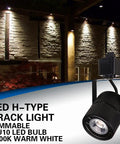 LED H-type track light in black with 3000K warm white illumination against a brick wall background