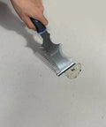 The Smooth Operator All In One Paint Brush And Roller Cleaning Tool with heavy duty steel blade scraping paint off a surface.