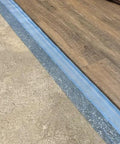 Game Changing 3in1 Vapor Barrier Flooring Underlayment With Pre Attached Tape For Laminate And Engineered Floors On Wood Or Cement Sub Floors Covers 100 Square Feet Quick Lay Down Smooth And Solid Finish, showing installation over concrete.