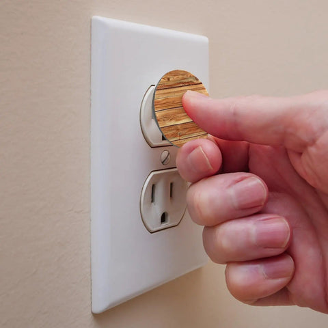 Hand installing Slick Pine Wood Texture Child Proof Outlet Covers For Wall Sockets on a white wall socket.