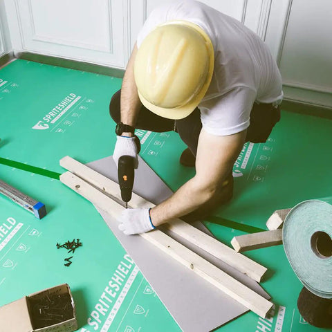 Worker using drill on wood with Pro Grade Heavy Duty Temporary Floor Protection Film For Construction And Renovation 39 Inch By 100 Foot Green Surface Shield For Hardwood Floors Tile And Painted Surfaces