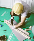Top Notch Temporary Floor Protection Roll For Construction And Home Reno Green Non Adhesive Surface Shield Film For Hardwood Floors Tile And Paint Heavy Duty Gear That Rolls Out Smooth And Keeps Surfaces Looking Brand New Today used by a worker drilling on floor.