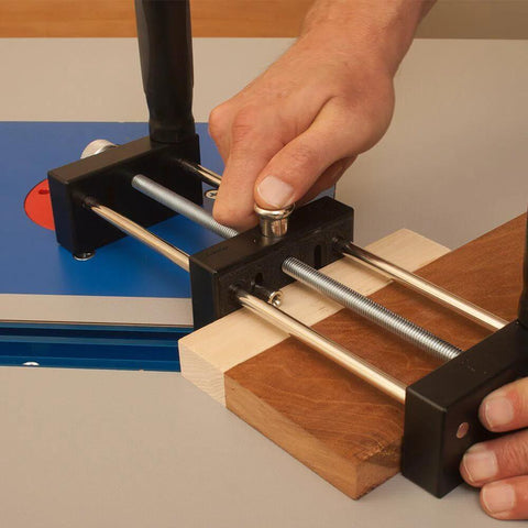 Close-up of a small stock holder for router tables securing tiny wood pieces, designed for safe feeding and precise freehand cuts.