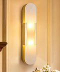 Natural Spanish Alabaster Wall Sconce, 19.7" High Marble Wall Sconces, G9 with gold metal base illuminating a wall.
