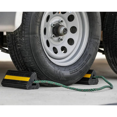 Heavy Duty Rubber Wheel Chock Set 4x4x8 With 36 Inch Nylon Rope securing truck tire, reflective tape visible, on concrete surface