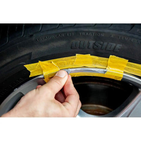 Applying liquid aluminum compound from Solid Alloy Wheel Repair Kit For Black Rims to fix curb rash on alloy wheel.