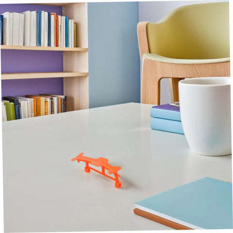 5 Piece Glider Plane Bracket Kit With Rubber Band Power For Do It Yourself Aircraft Builds on a desk with books and chair.