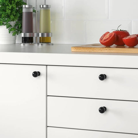 Matte Black Cabinet Knobs Four Pack With Wide Backplates on white kitchen drawers next to sliced tomatoes and condiments
