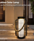 Big Solar Powered Lantern for Outdoor Use with metal frame and rope handle on patio steps at night.