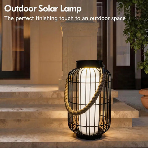 Big Solar Powered Lantern for Outdoor Use with metal frame and rope handle on patio steps at night.