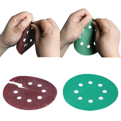 Hands demonstrating flexibility of 5 inch sanding discs, showcasing red and green discs with holes for hooks and loops.