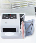 Money Counter Machine With UV MG WM Counterfeit Detection on a desk next to a laptop, displaying bill insertion and LED display.