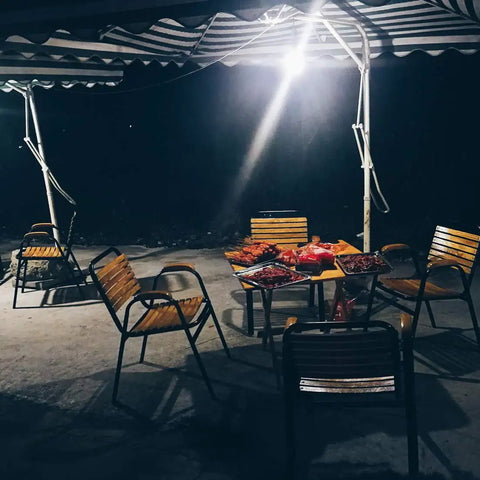 Outdoor dining area at night illuminated by Ultra Bright Outdoor LED Motion Sensor Flood Light 12-24V AC/DC Waterproof Security Lamp.