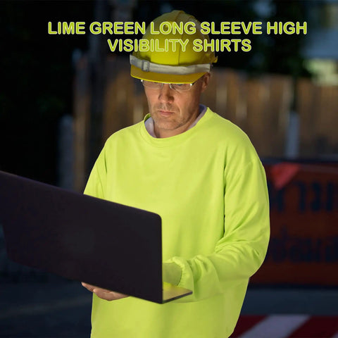 Person wearing high visibility long sleeve work shirt using laptop in outdoor night setting, lime green color, hard hat visible.