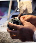 Hand using 120Pcs Wool Felt Polishing Wheel Set With Mounted Shank For Rotary Tools on metal jewelry, side view, in use
