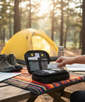 MediKit medical kit, black zippered case open with interior pockets on camping table; tent in background.