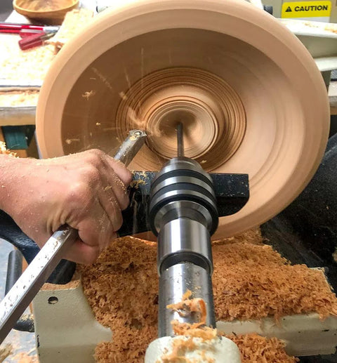 Carbide wood lathe detailer turning tool, unhandled, stainless steel, in use on spinning wooden bowl