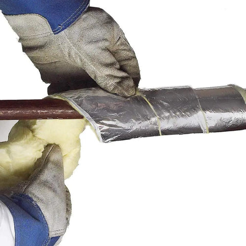 Hands wrapping foil-backed fiberglass pipe wrap 3 inch by 1 inch by 25 feet around a pipe for insulation in plumbing projects.