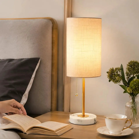 Gold Table Lamps Set Of 2 For Bedside And Living Room With Marble Bases Linen Shade Pull Chain 3 Way Dimmable Nightstand Lamps 18.5 Inch Tall Slim Desk Style Bulbs Included on nightstand next to bed, cup, and flowers in vase.
