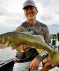 Angler on a boat holding a walleye fish, showcasing successful catch using Rock Runner Slip Bouncer Weight With Quick Change Precision Sinker.