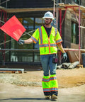 Mens Built Tough High Visibility Mesh Vest With Six Cargo Pockets And Secure Zipper Ansi Class Three worn by a construction worker holding a flag.